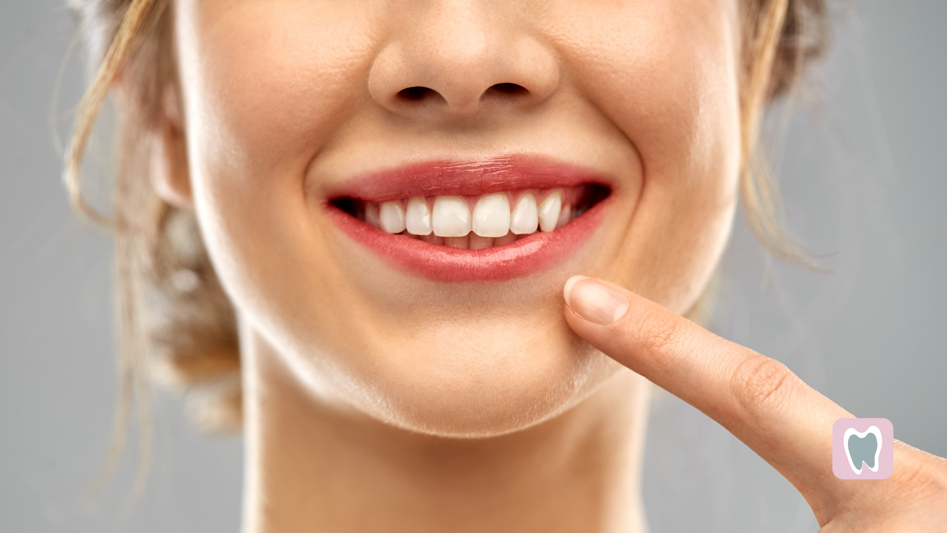 A woman is pointing at her teeth with her finger.