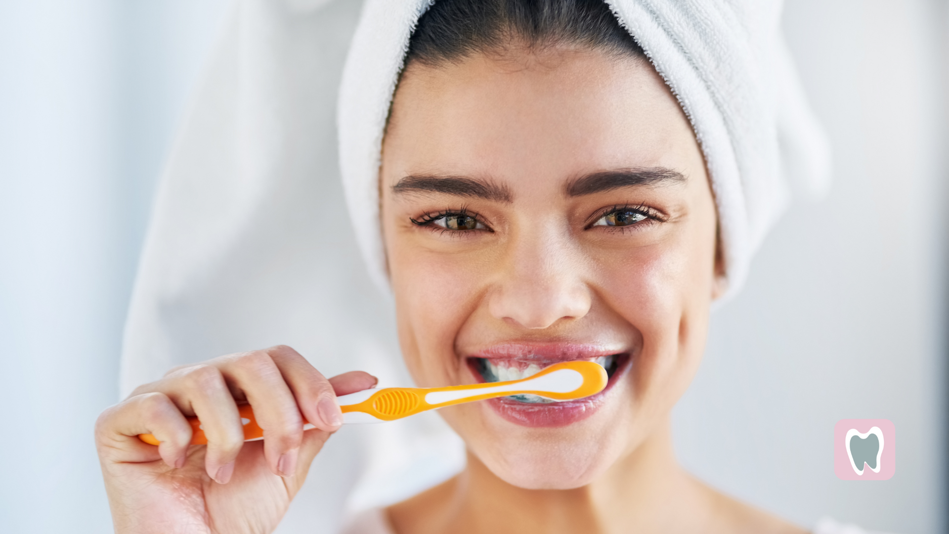 A woman with a towel wrapped around her head is brushing her teeth.