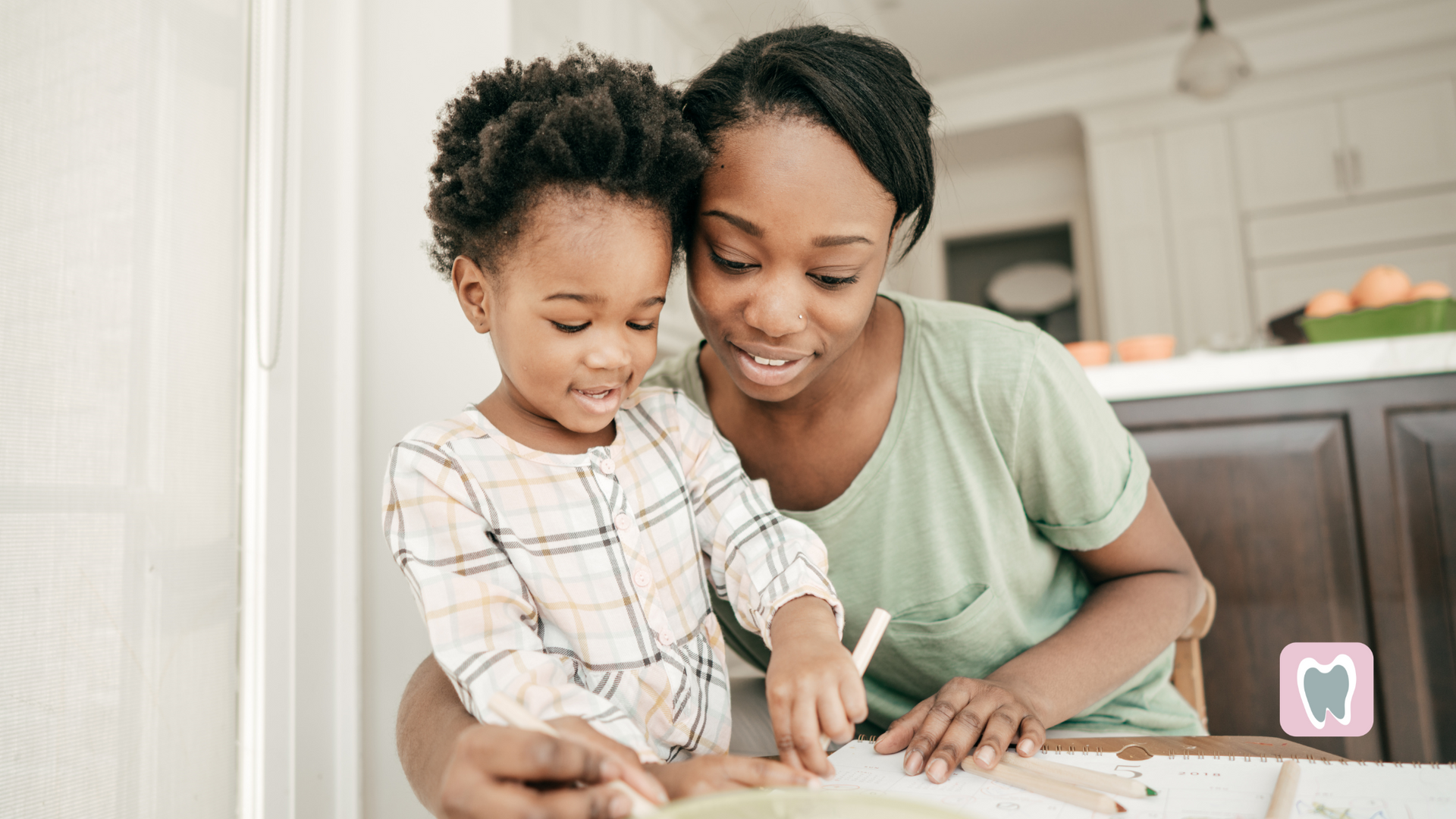 A woman and a child are sitting at a table drawing with pencils.