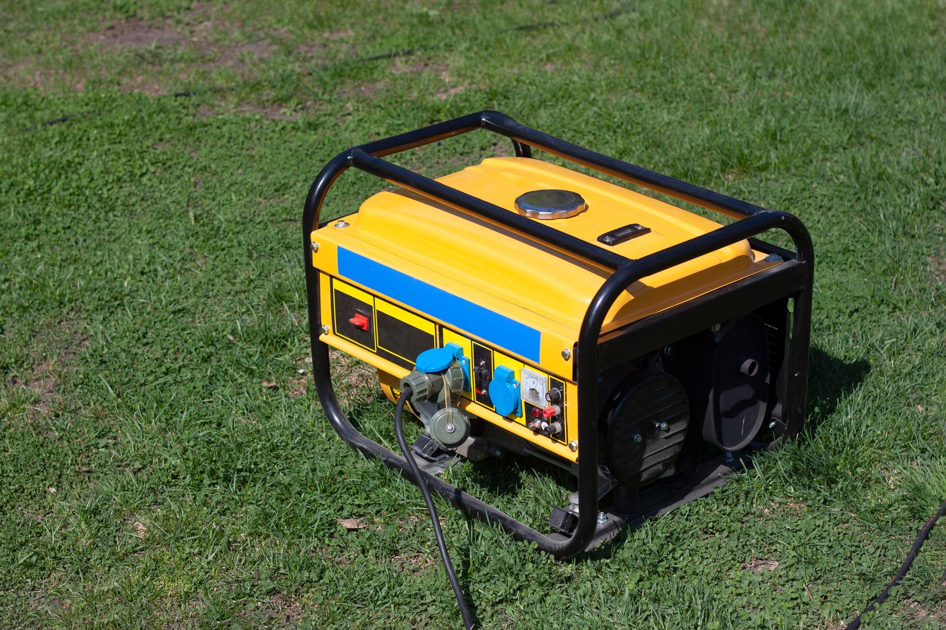 A yellow generator is sitting on top of a lush green field.