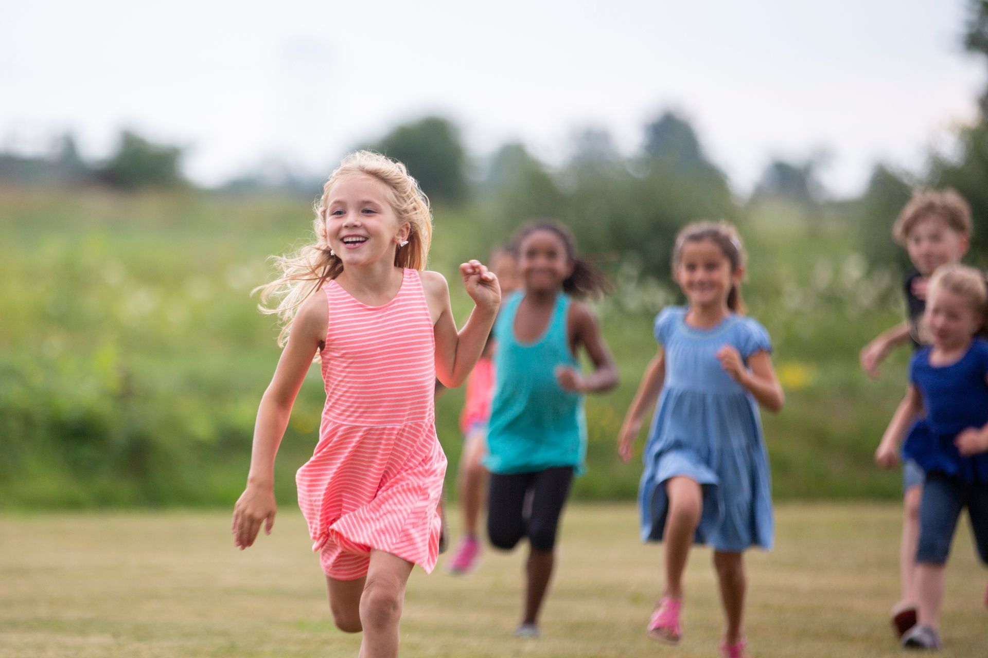 A group of children are running in a field.