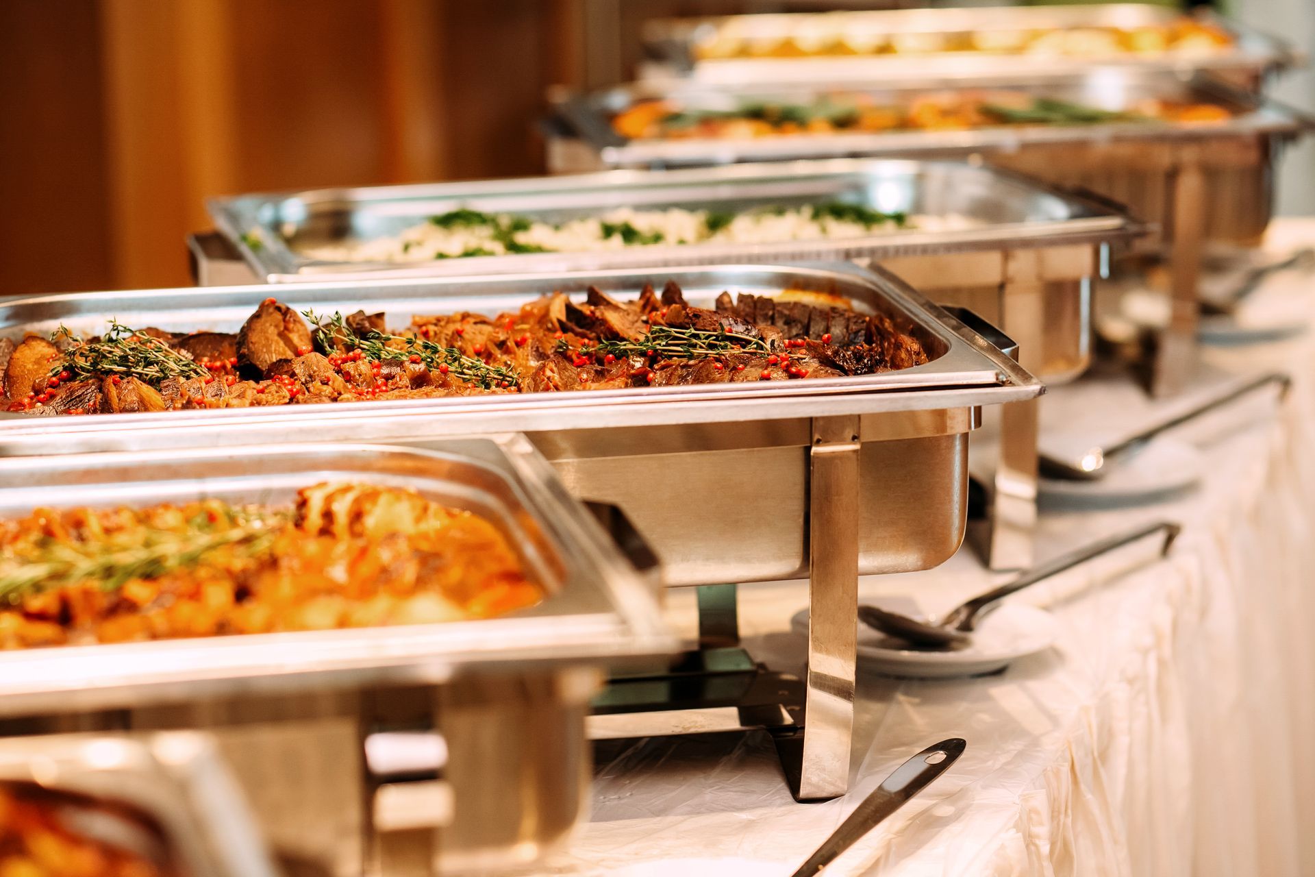 A row of buffet trays filled with food on a table.