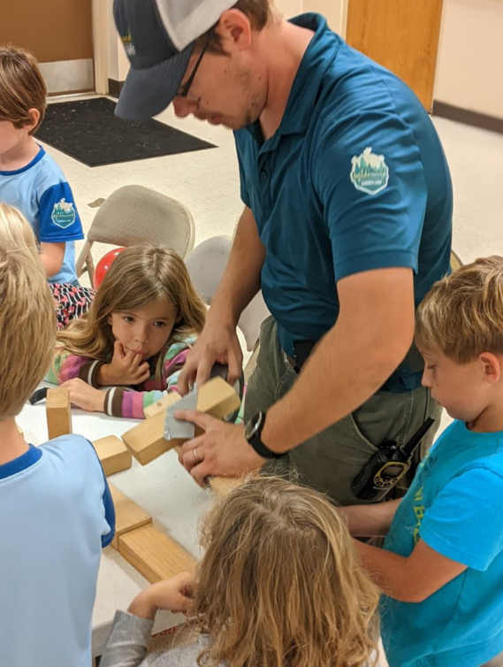 A man in a blue shirt is playing with a group of children