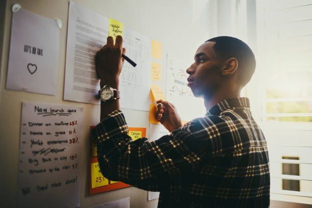 A man is writing on a whiteboard with sticky notes.