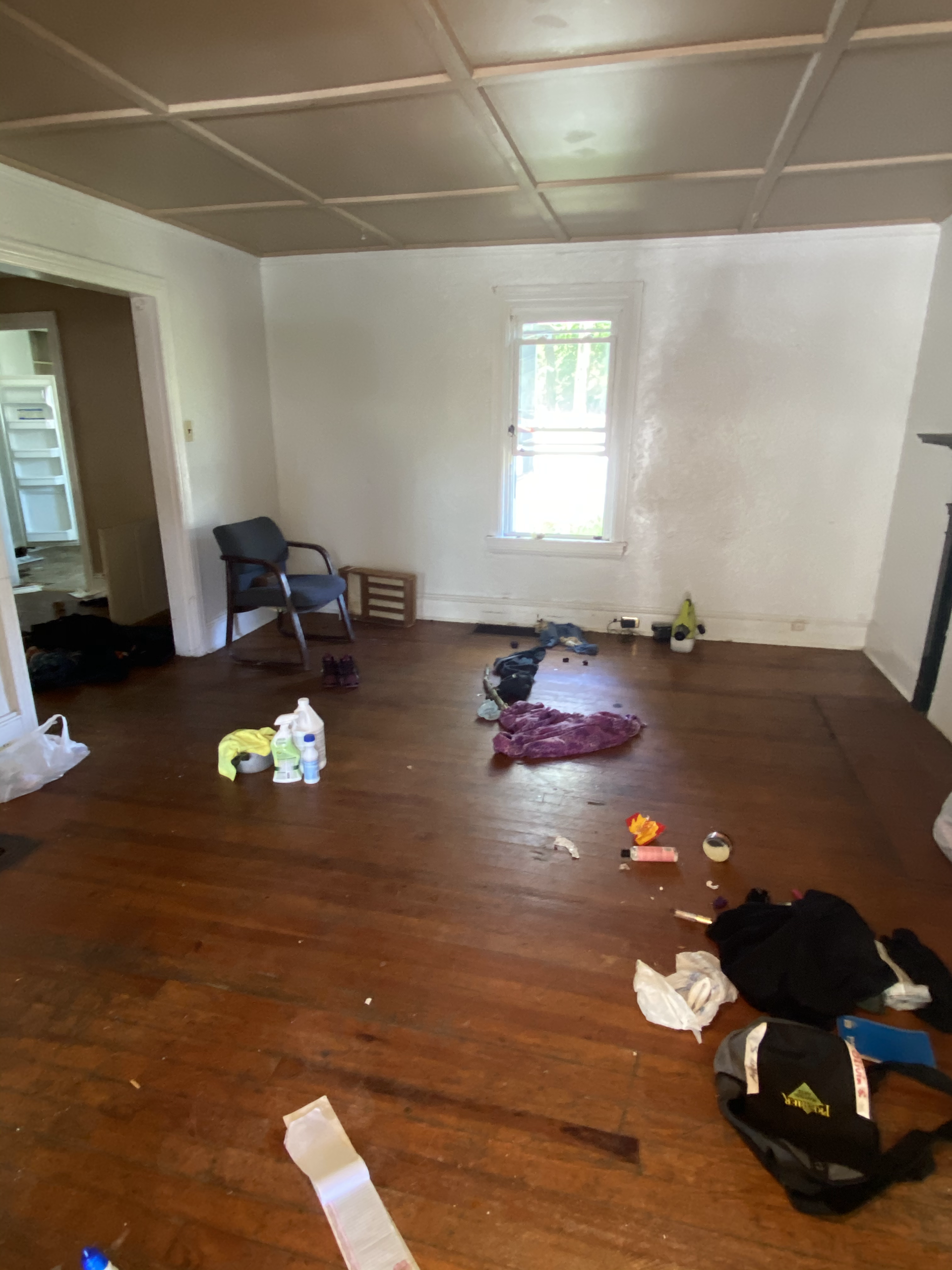 An empty living room with a wooden floor and a chair.