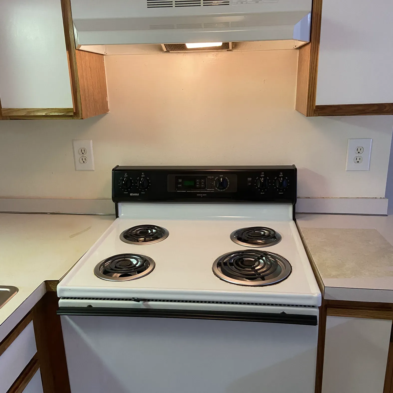 A white stove with four burners is in a kitchen