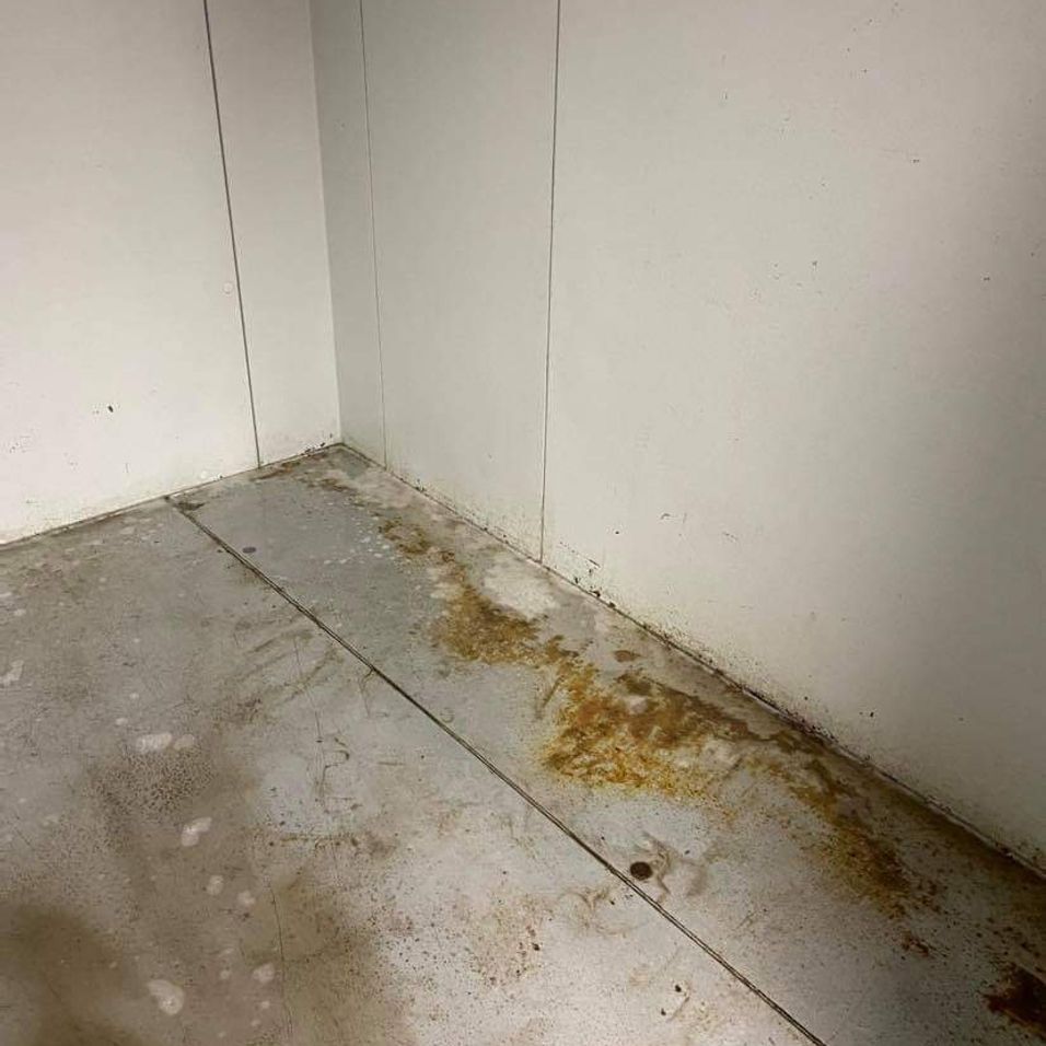 A dirty room with white walls and a dirty floor.