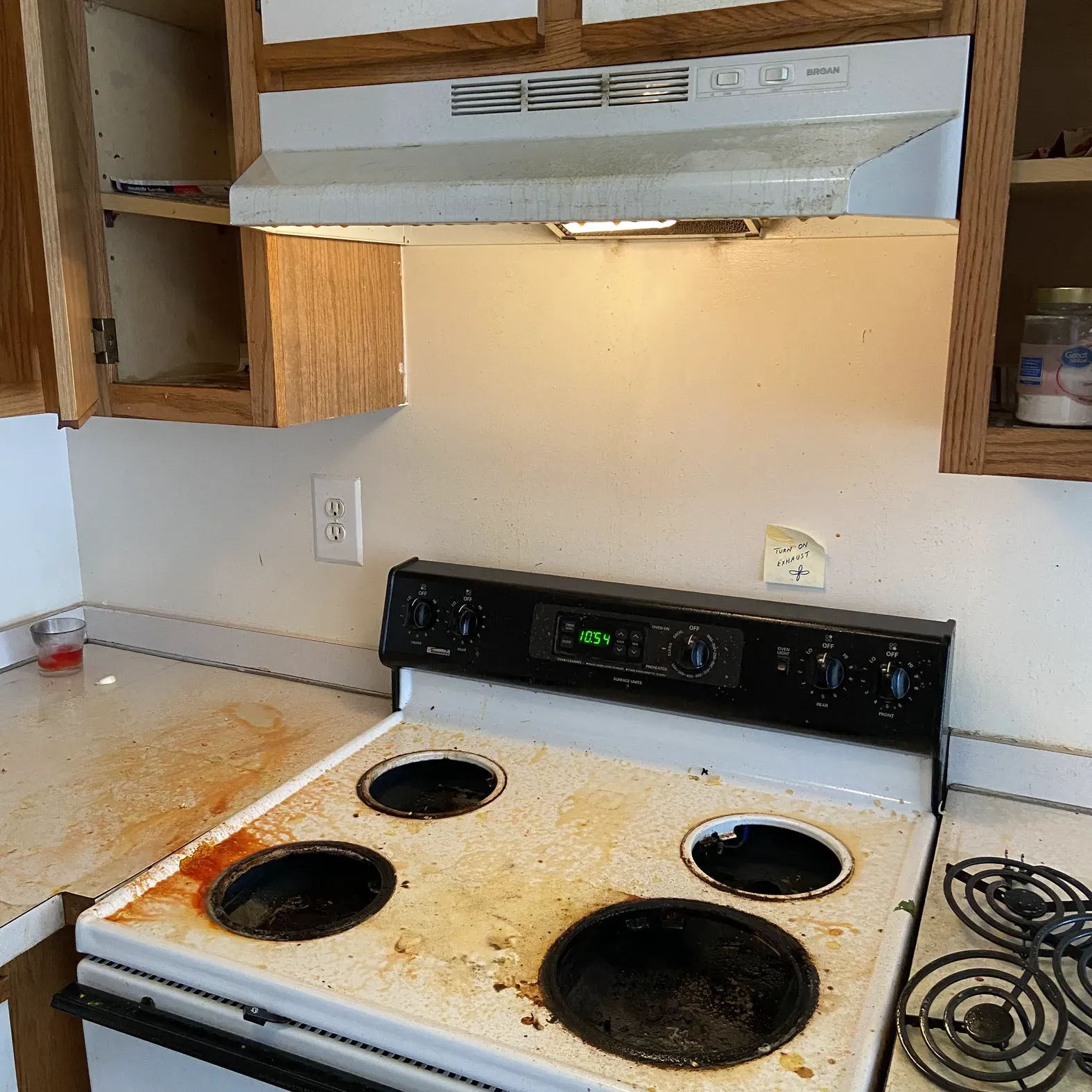 A dirty stove with a hood that says ' sss ' on it