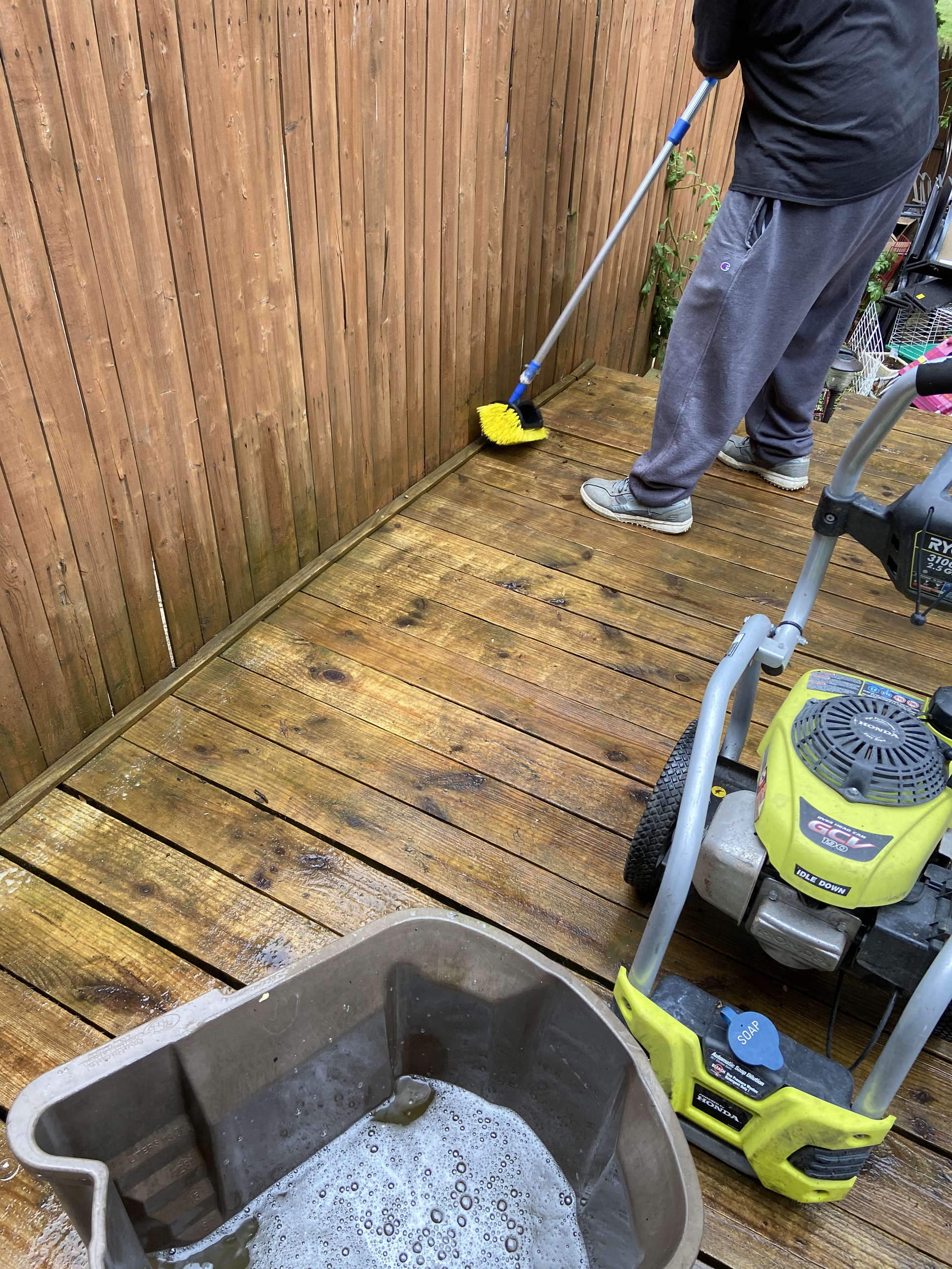 A man is cleaning a wooden deck with a pressure washer.