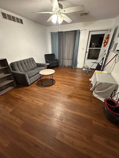 A living room with a couch , chair , table and ceiling fan.
