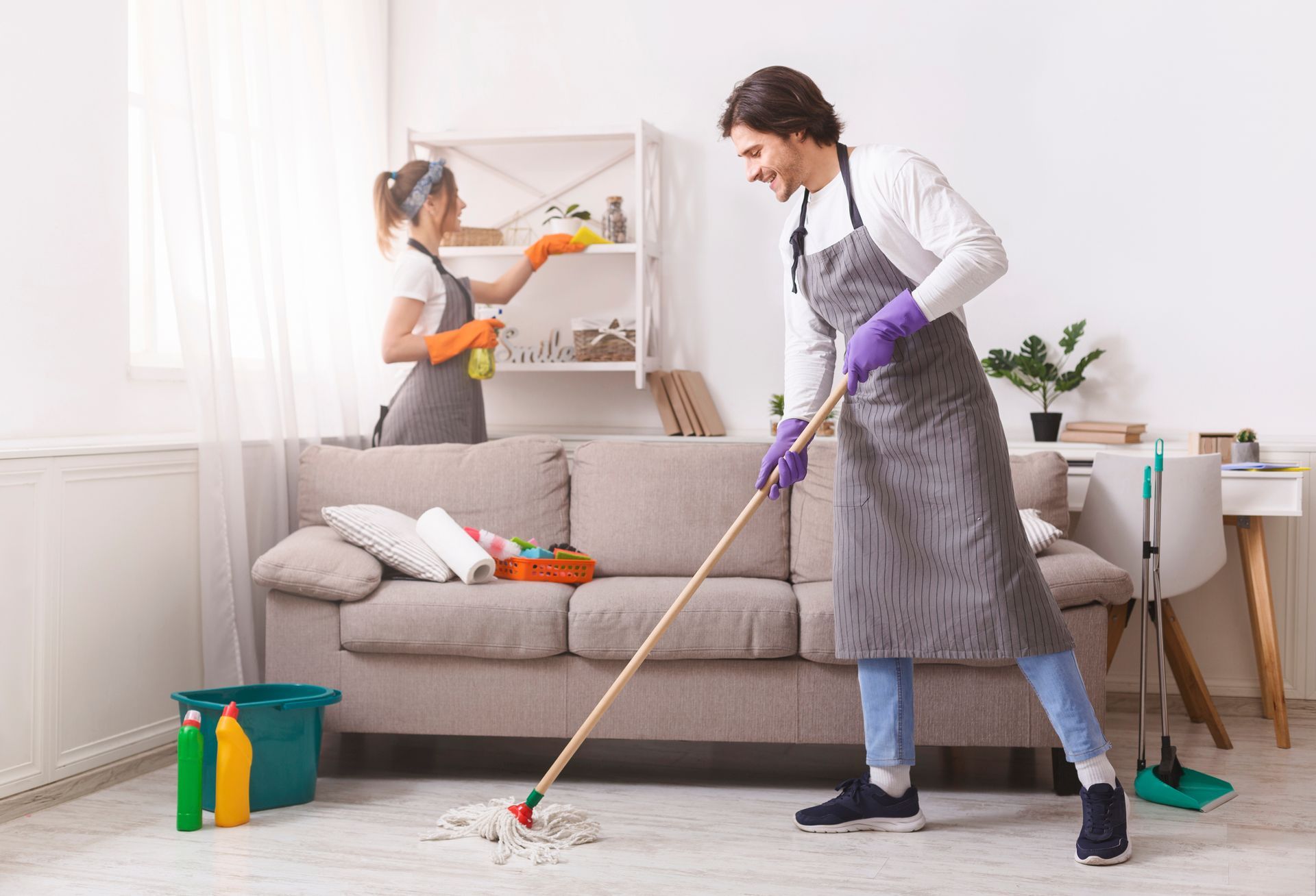 A man and a woman are cleaning the floor in a living room.