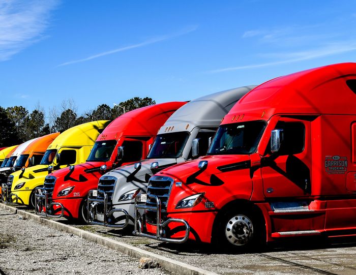 Trucker wearing R.E. Garrison Hat standing in front of Garrison Truck focused on Logo