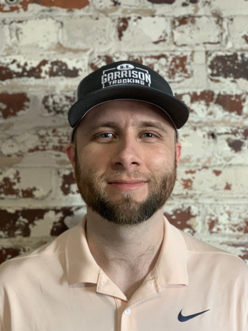 Nathan Wright wearing a tan shirt and black hat in front of a brick wall