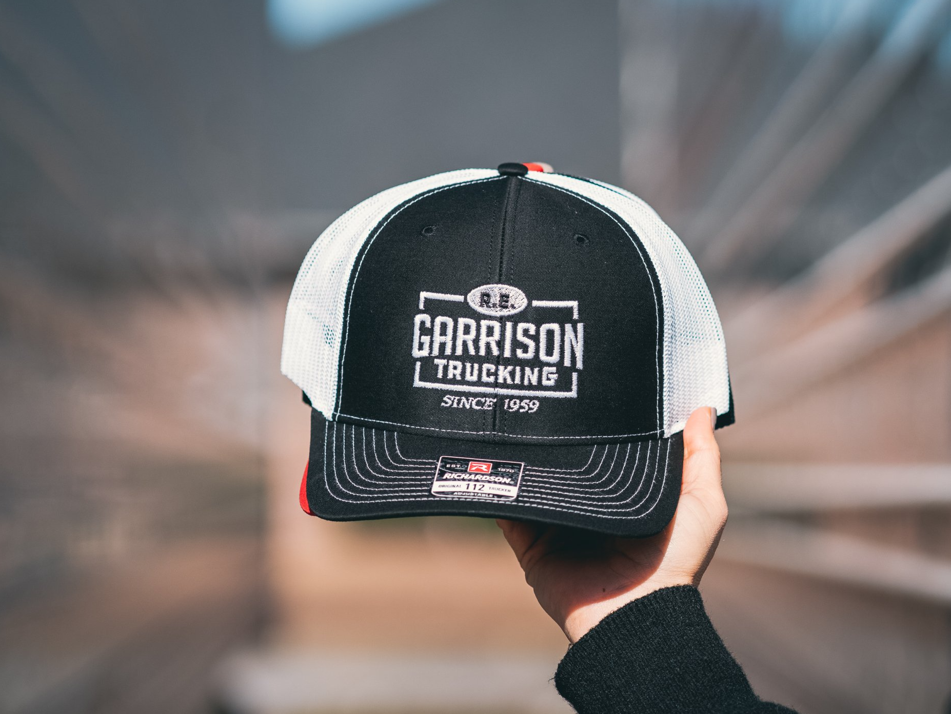 Hand Holding a black and white R.E. Garrison Hat