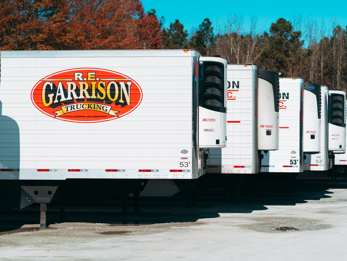 Trucker wearing R.E. Garrison Hat standing in front of Garrison Truck focused on Logo