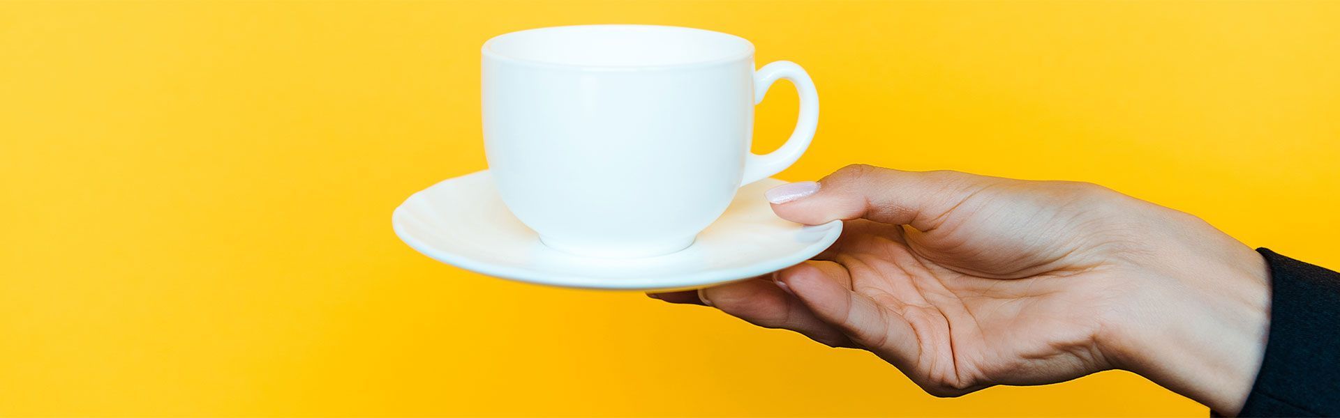 A person is holding a cup of tea on a saucer.