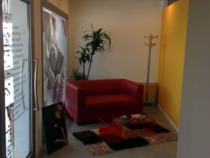 Comfortable sala d'attesa con tappeto di colori, un sofà rosso e piante