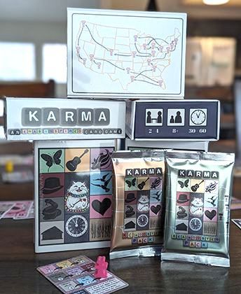 A photo of the Karma card game prototype, showing all sides of the packaging, Taylor Swift's tour route, and two booster packs.