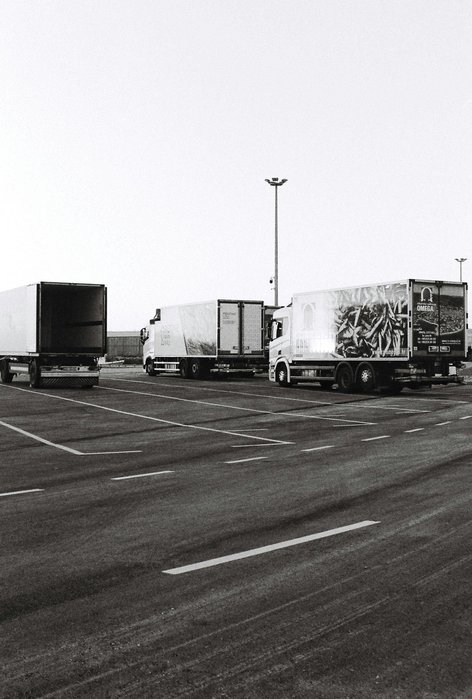 A black and white photo of trucks parked on the side of the road