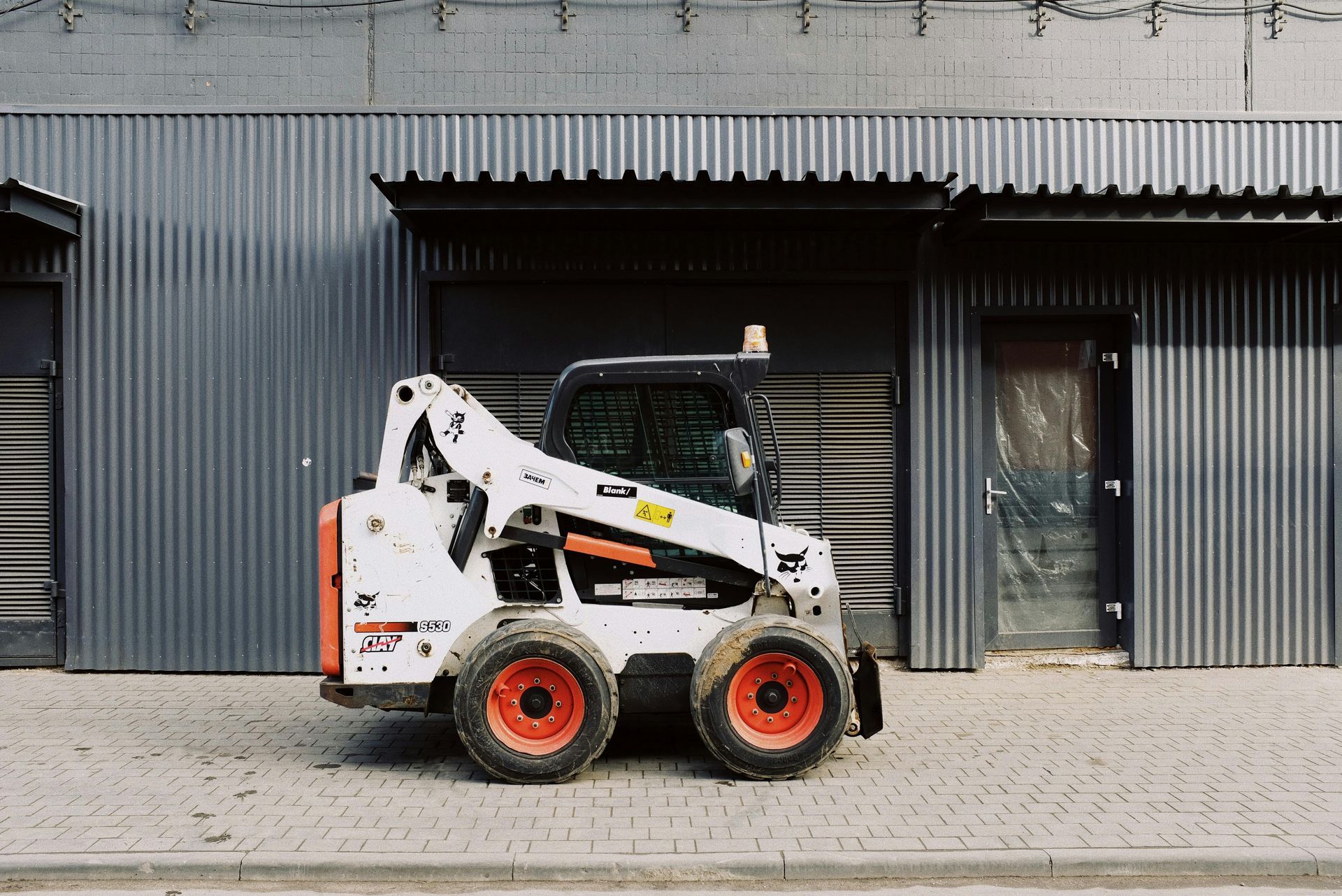 A small bulldozer is parked in front of a building.