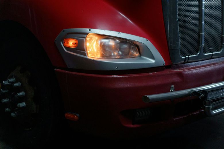 A close up of a red truck 's headlight in a dark room.