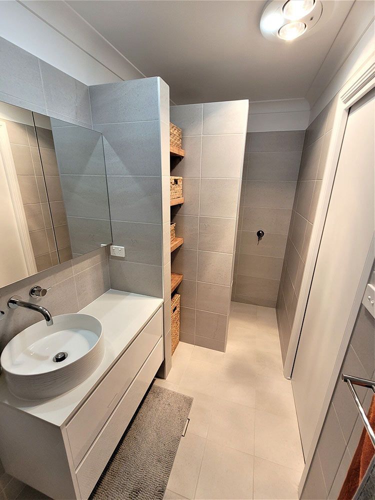 A Bathroom With A Sink, Mirror, And Walk In Shower — Chandolin Construction In Robin Hill, NSW