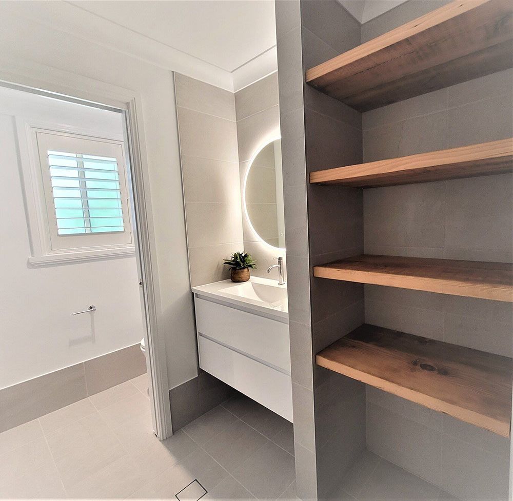 A Bathroom With A Sink, Mirror And Shelves — Chandolin Construction In Robin Hill, NSW