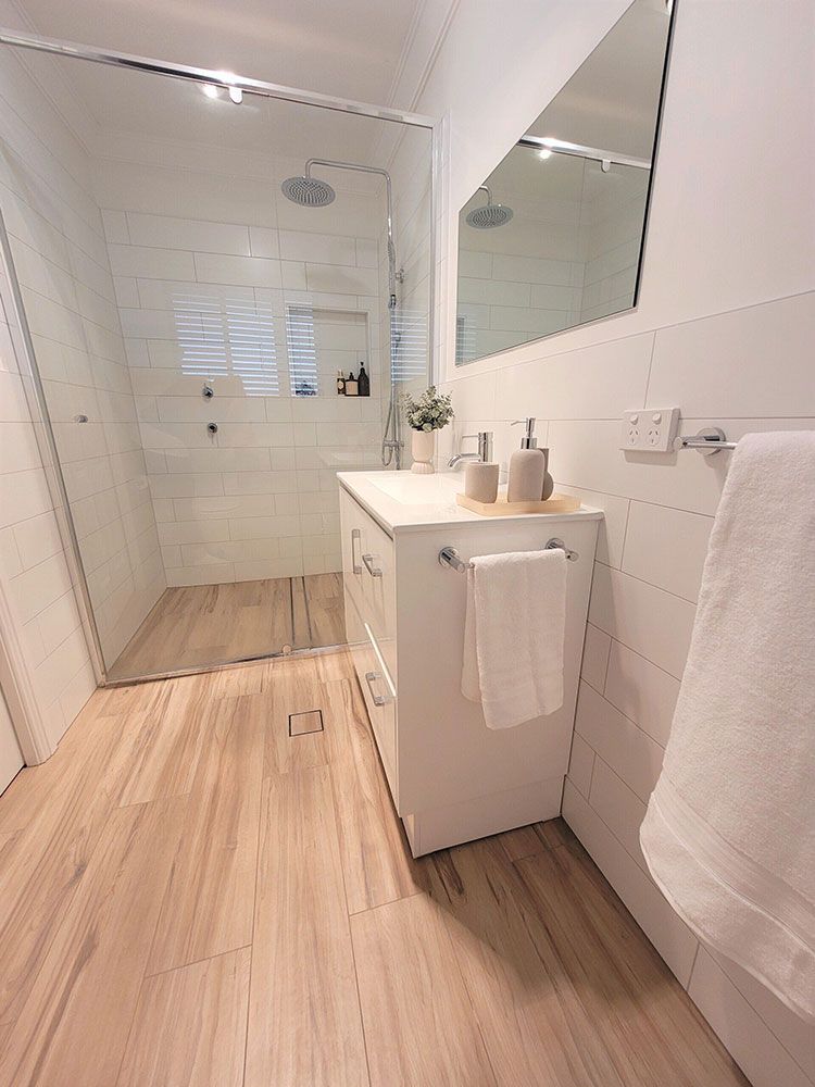 A Bathroom With A Sink, Mirror And Walk In Shower — Chandolin Construction In Robin Hill, NSW