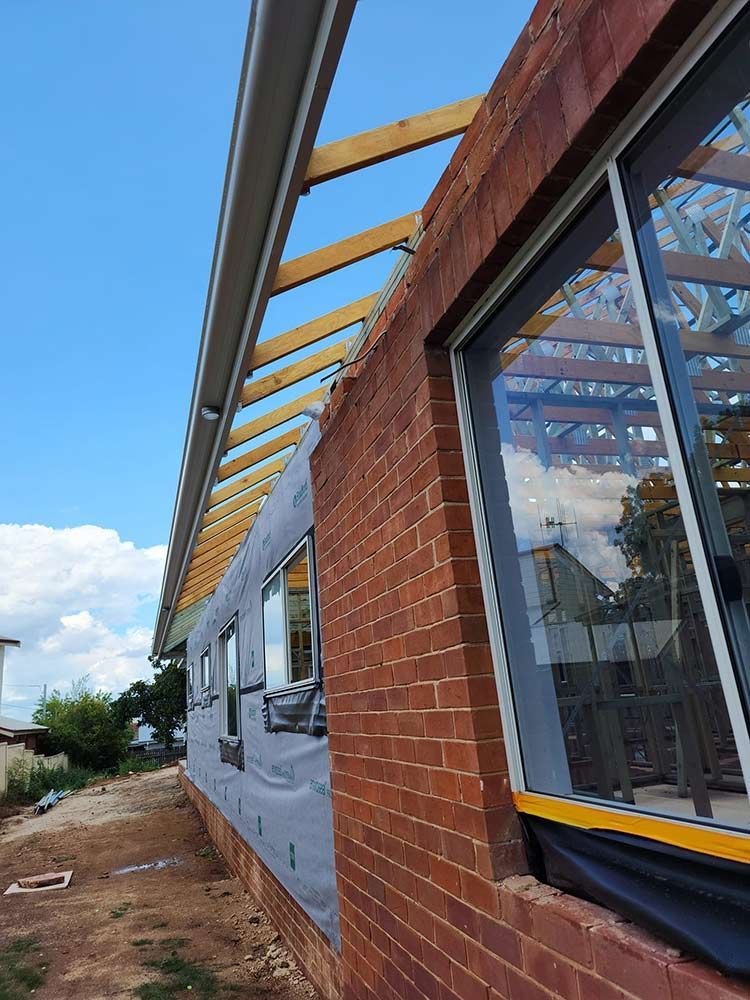 A Brick Building Under Construction With A Wooden Roof And Windows — Chandolin Construction In Robin Hill, NSW