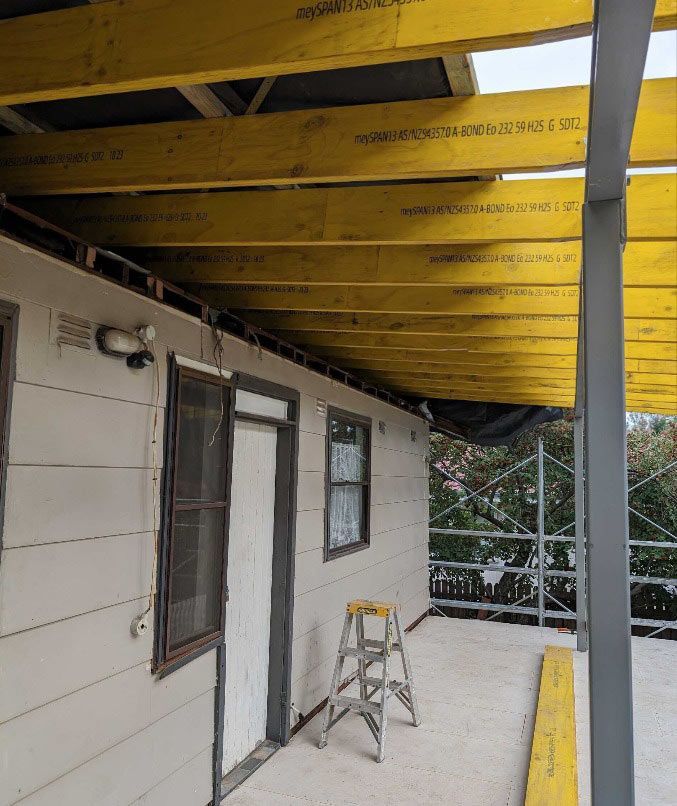 A Ladder Is Sitting On The Side Of A Building Under A Wooden Roof — Chandolin Construction In Robin Hill, NSW