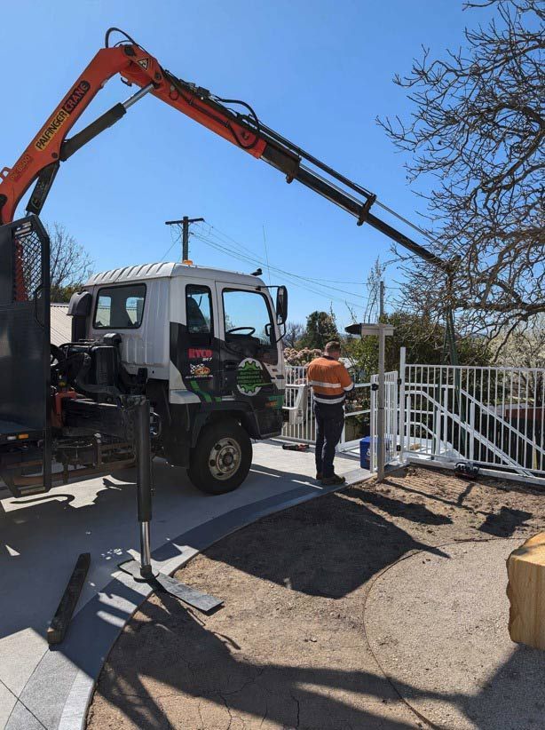 A Man Is Standing Next To A Truck With A Crane Attached To It — Chandolin Construction In Robin Hill, NSW