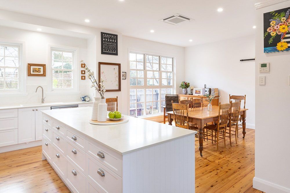 A Kitchen With White Cabinets And A Large Island — Chandolin Construction In Robin Hill, NSW