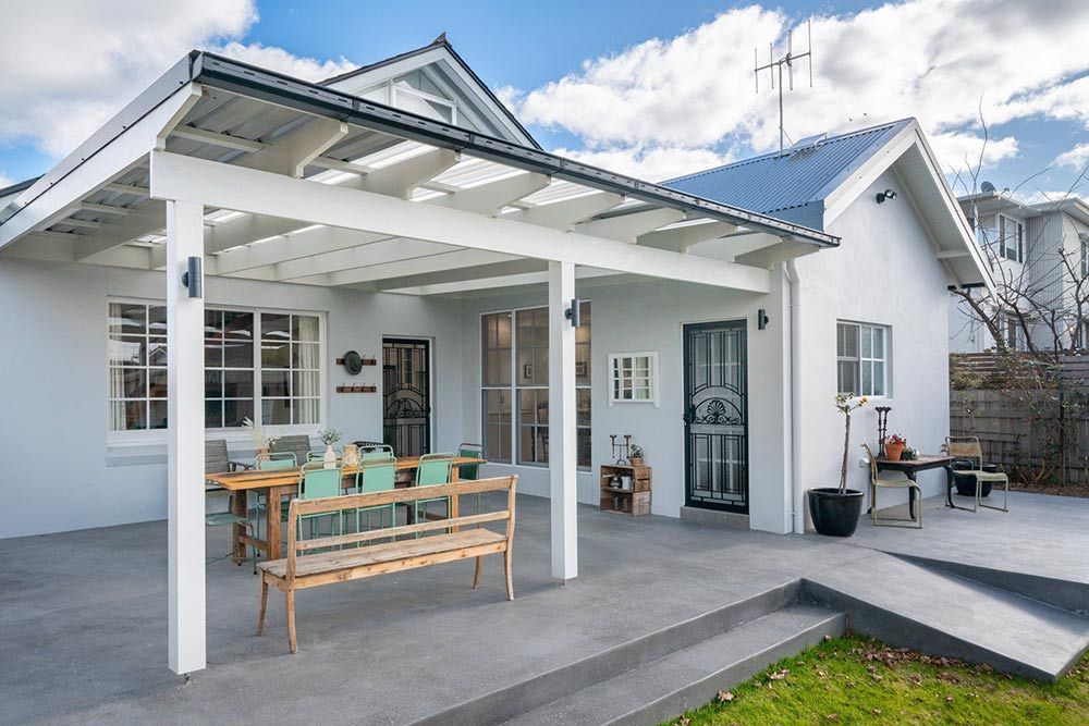 A White House With A Covered Patio With A Table And Chairs — Chandolin Construction In Robin Hill, NSW