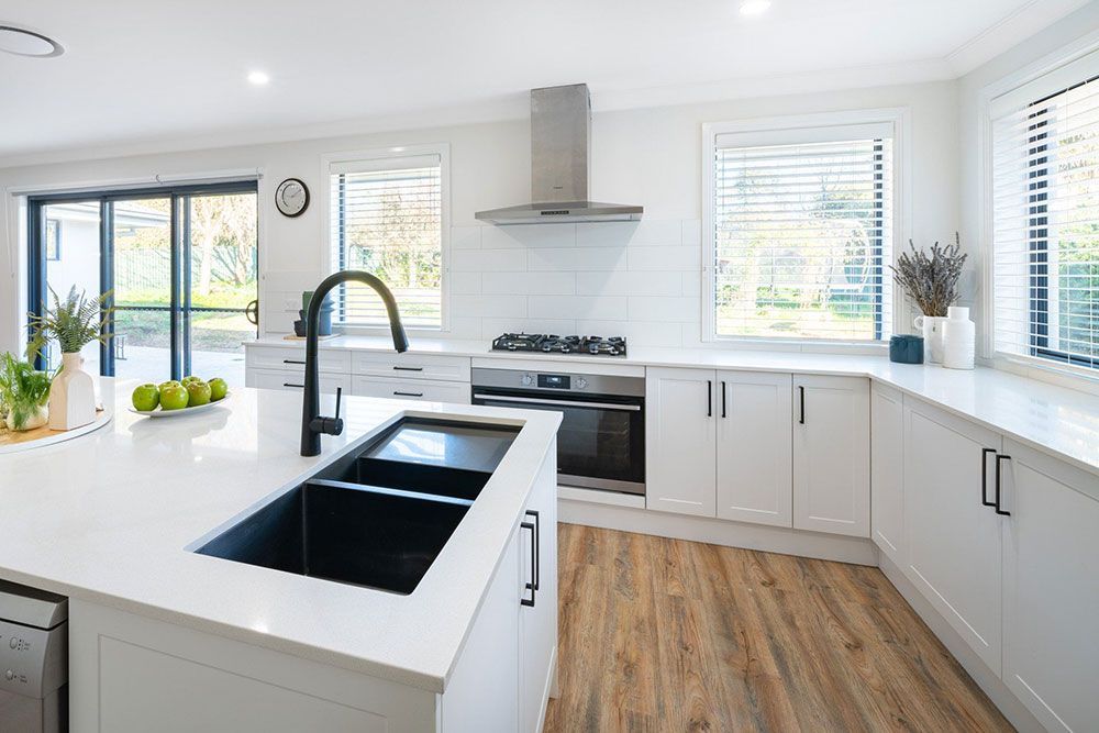 A Kitchen With White Cabinets And A Black Sink — Chandolin Construction In Robin Hill, NSW