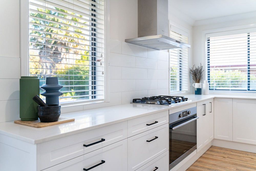 A Kitchen With White Cabinets  And A Window — Chandolin Construction In Robin Hill, NSW