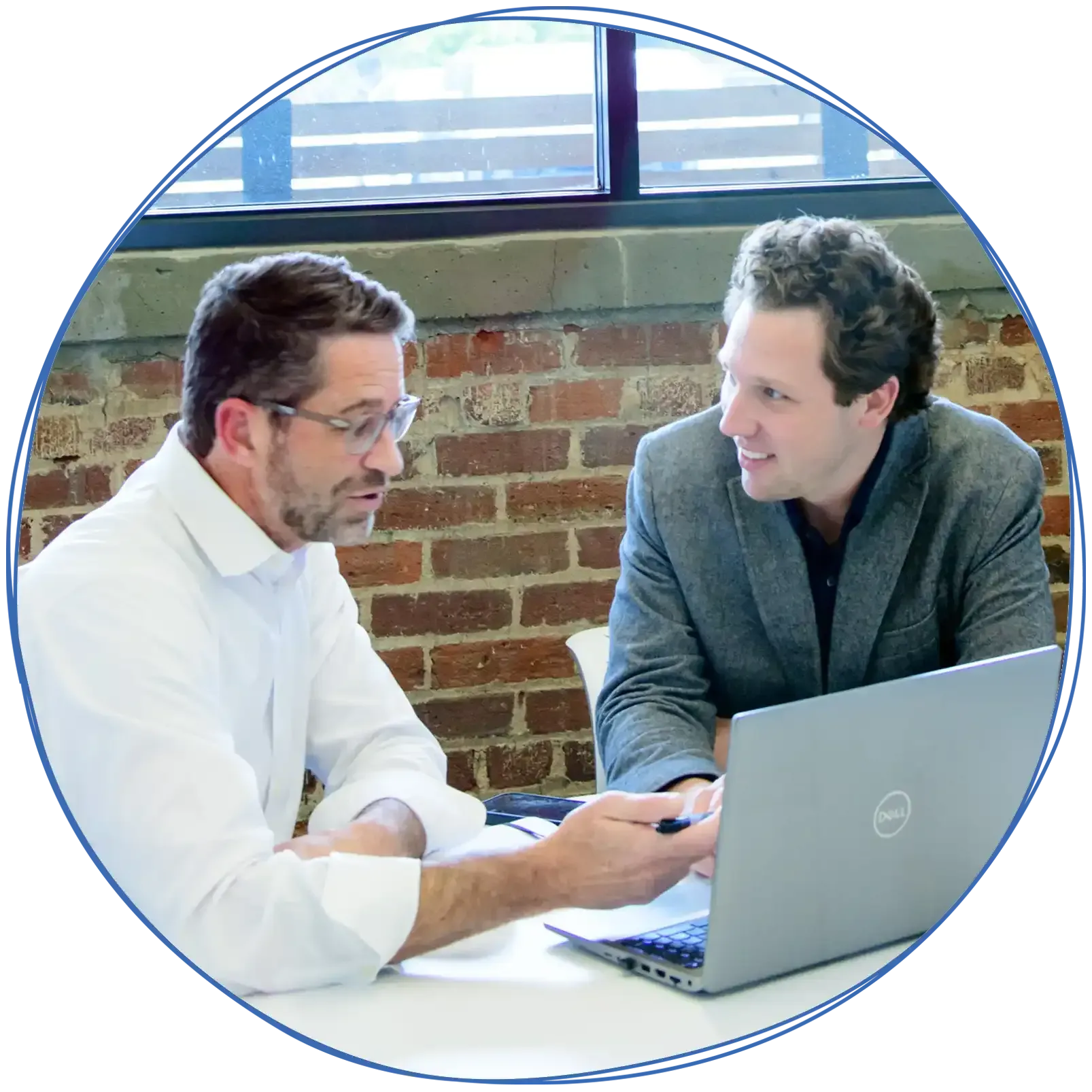 People in a business meeting around a table, using laptops and discussing ideas. Blue and white colors.