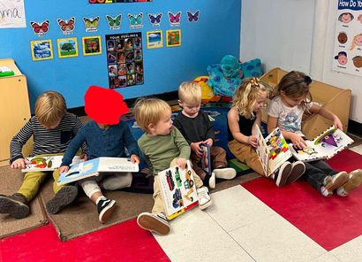 A colorful preschool classroom with blue walls, shelves, educational materials, and a wooden door.