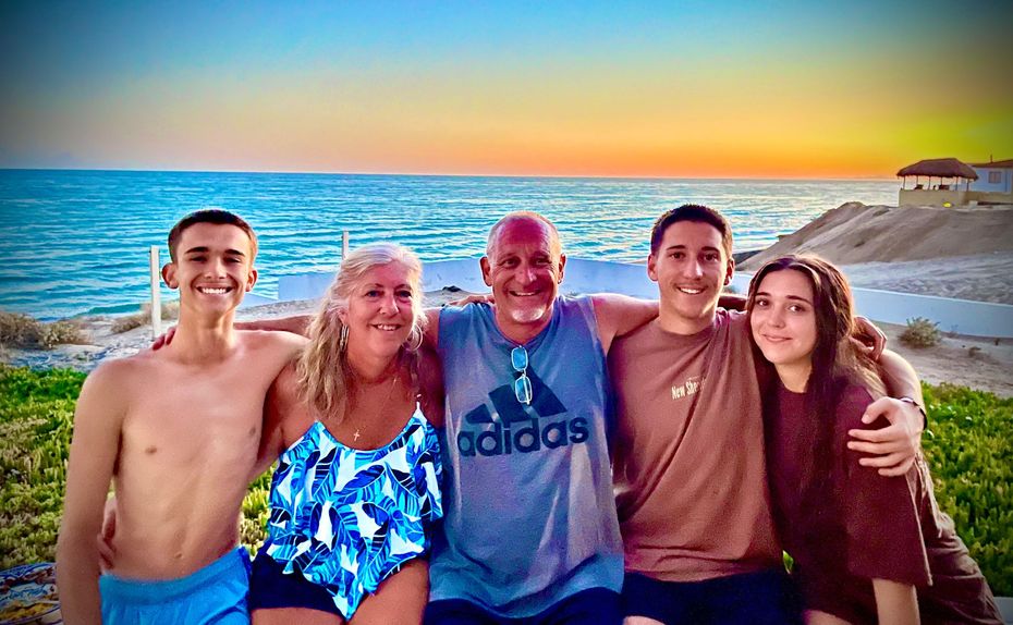 Family smiling together on a beach, sunset sky and ocean background.