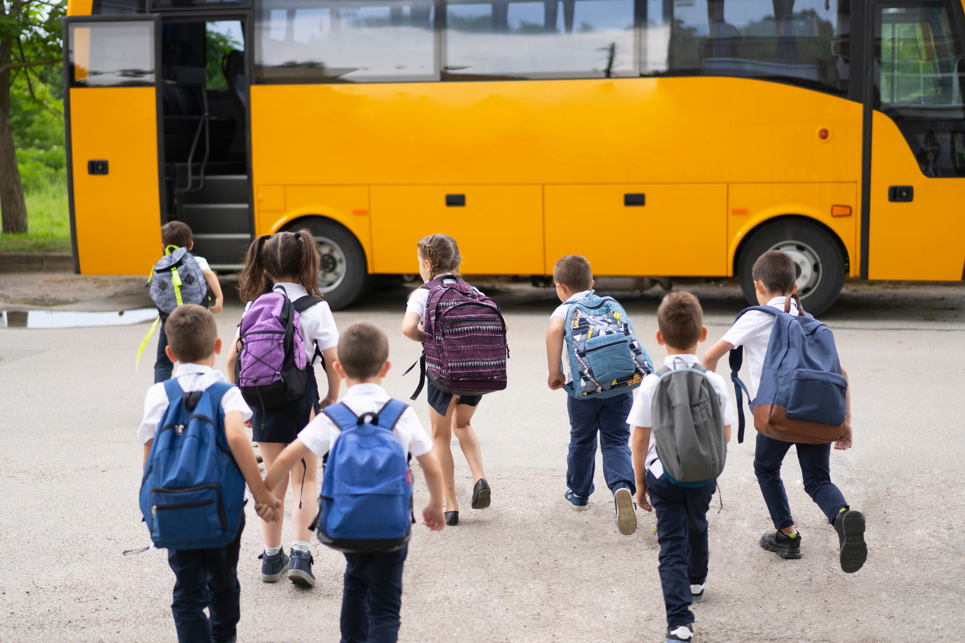Children with backpacks boarding a yellow school bus.