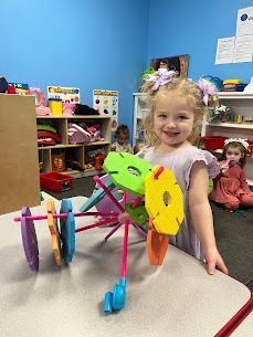 Outdoor play area with pink awning, colorful toys, and artificial turf.