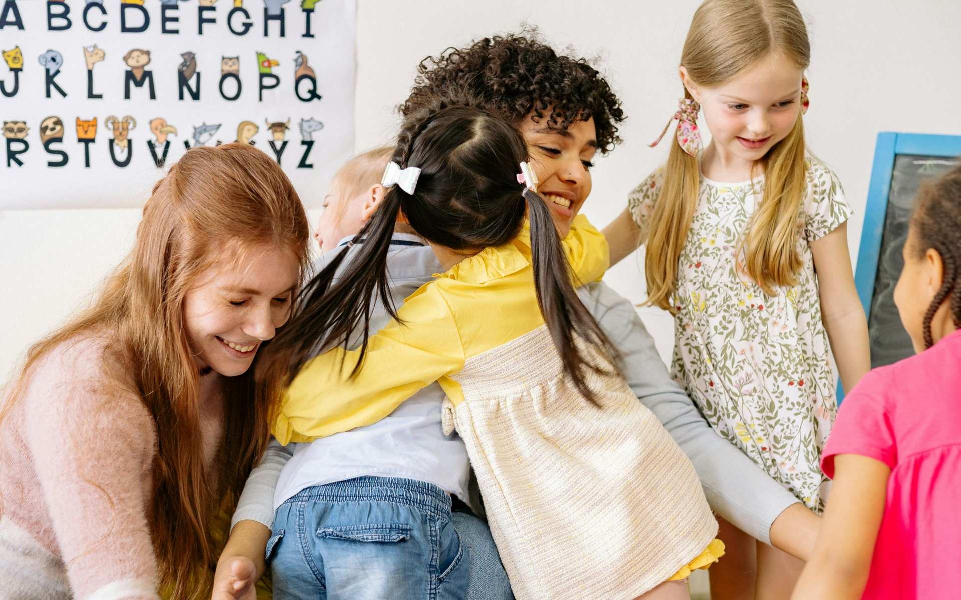 Child with very light blonde hair, lying on a colored court, shielding eyes with hands.