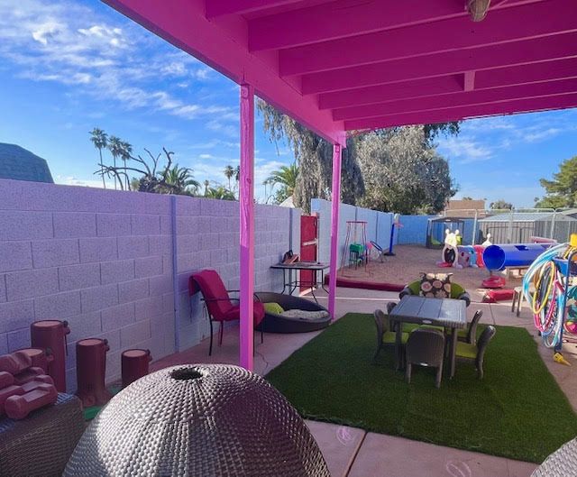 Outdoor patio with pink awning, furniture, artificial grass, and play equipment.