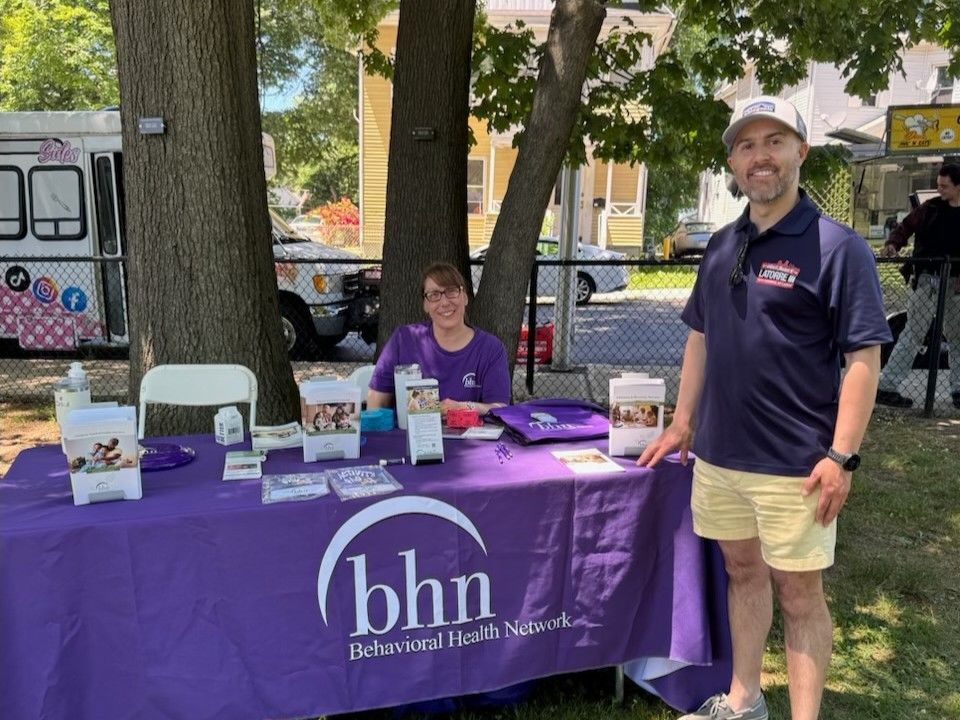 A photo of our staff member, Lisa, sitting at our BHN table with Springfield Council Candidate, Jay Latorre III, joining her for a photo. This photo was taken at BHN's mental health awareness community event in the park.