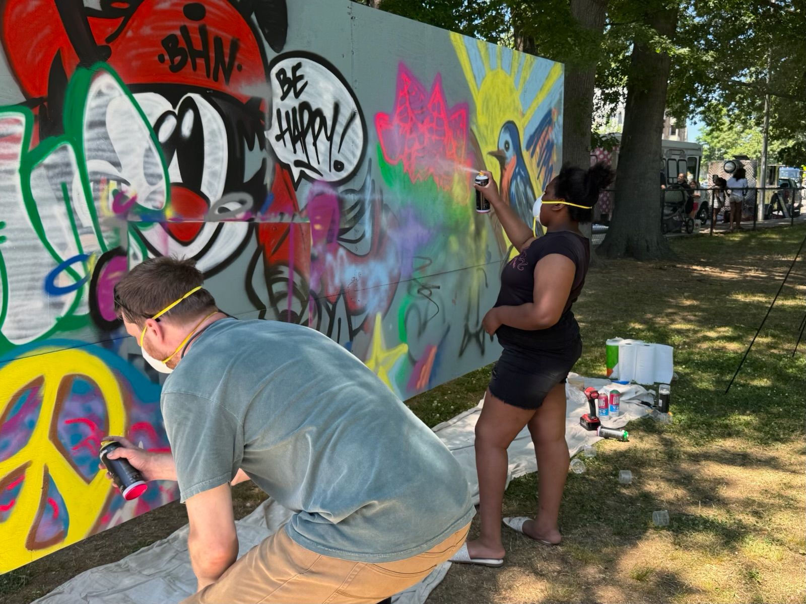 A man and a little girl creating graffiti art on a large wall
