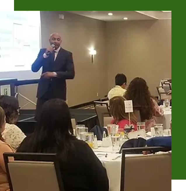 A man is giving a presentation to a group of people sitting at tables.