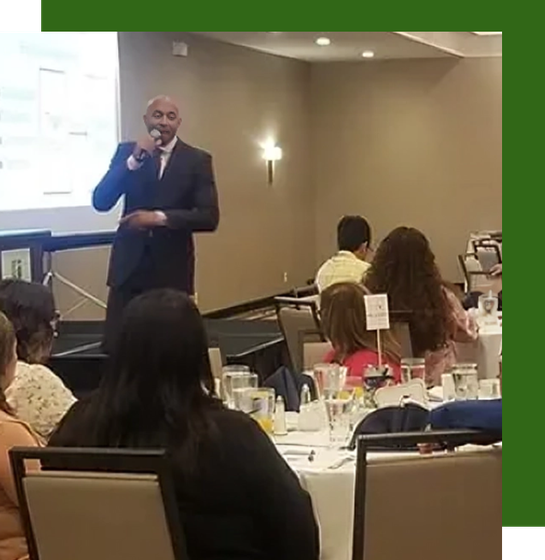 A man is giving a presentation to a group of people sitting at tables.