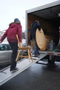 A man is loading a chair into a truck on a ramp.