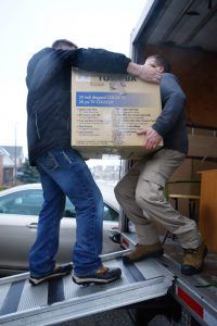 Two men are carrying a box out of a truck.