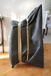 A chair is wrapped in a blanket and sitting on a wooden floor.