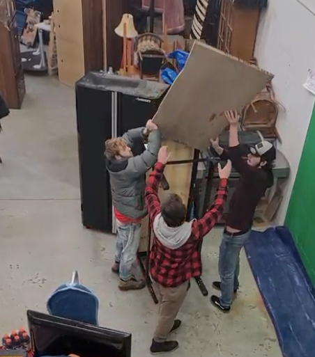 A group of people are lifting a large piece of cardboard